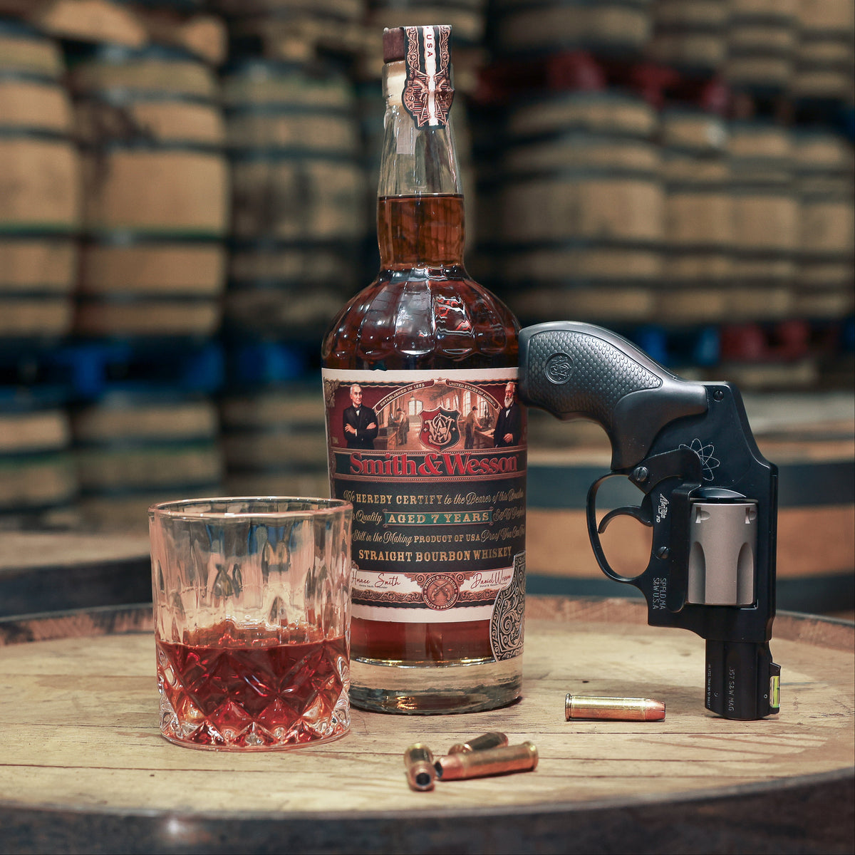 Smith & Wesson™ Classic Collection on top of a barrel with whiskey glass, gun shell casings and gun